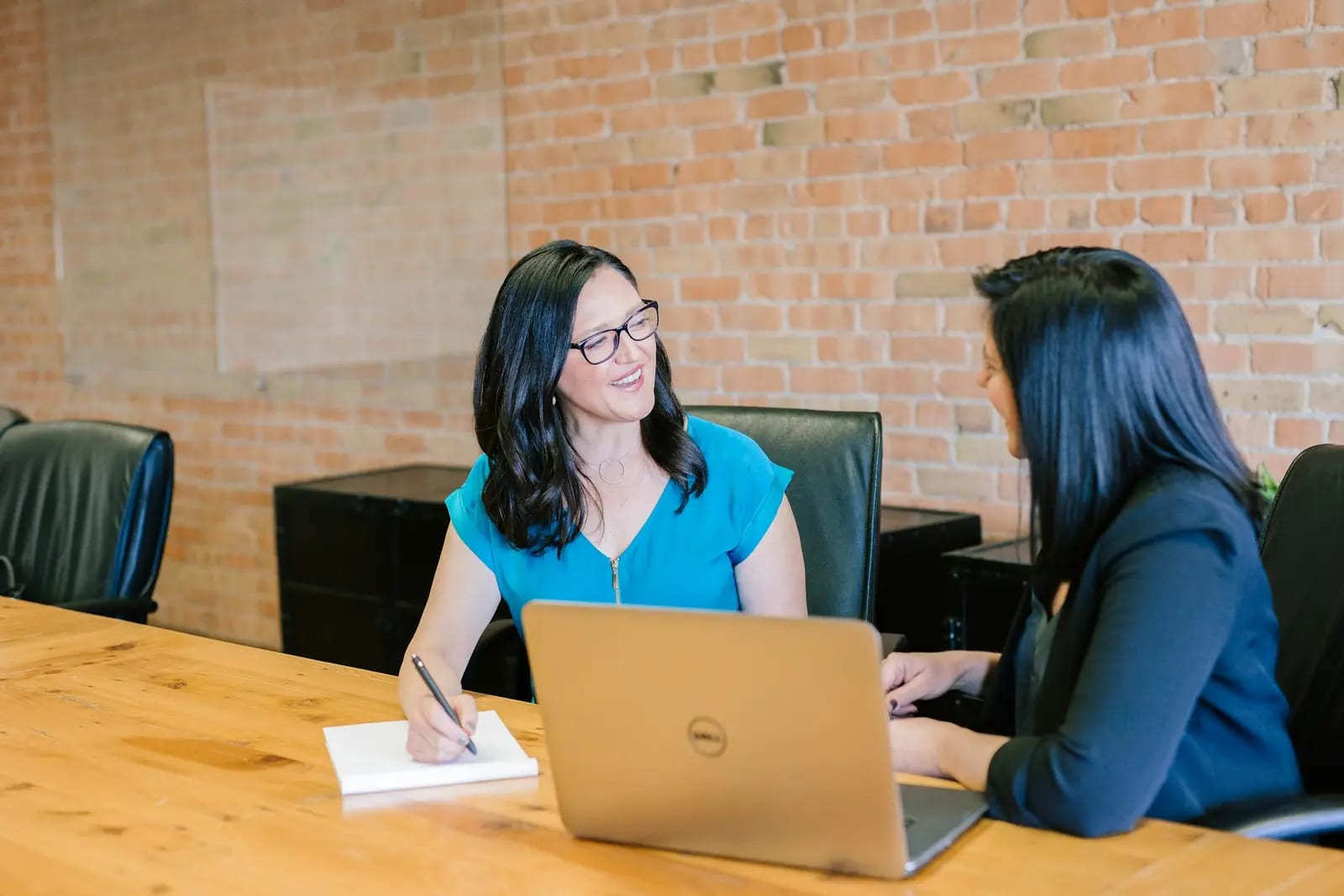 Two professionals discussing work across a laptop